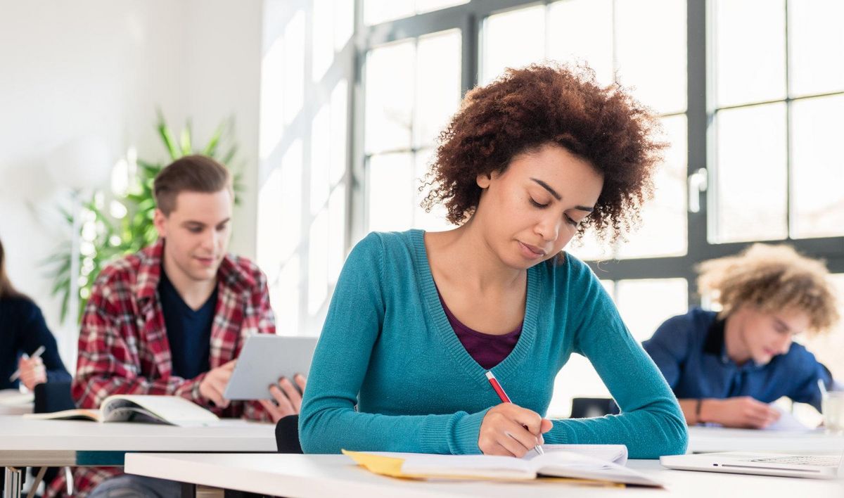 zur Vergrößerungsansicht des Bildes: Eine Gruppe Studierender schreibt eine Prüfung.